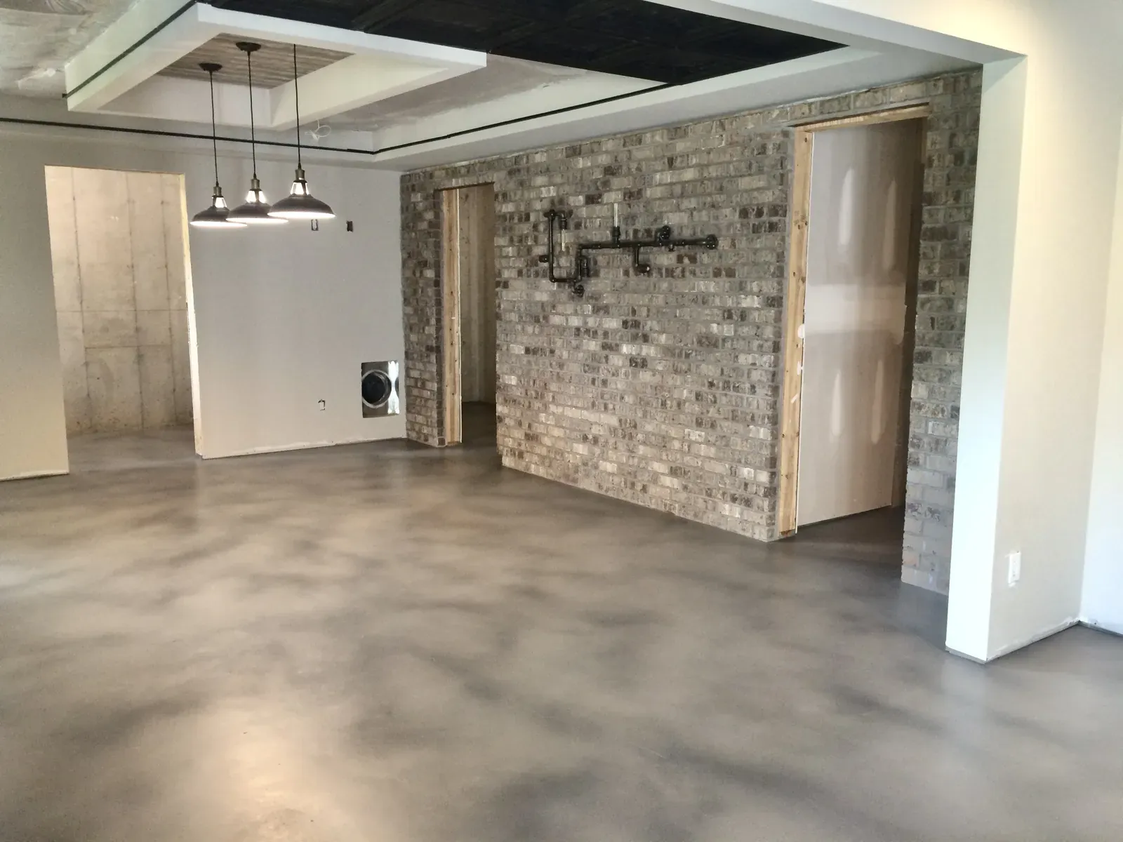 Modern gray stained concrete basement floor beside a brick accent wall in Acworth GA