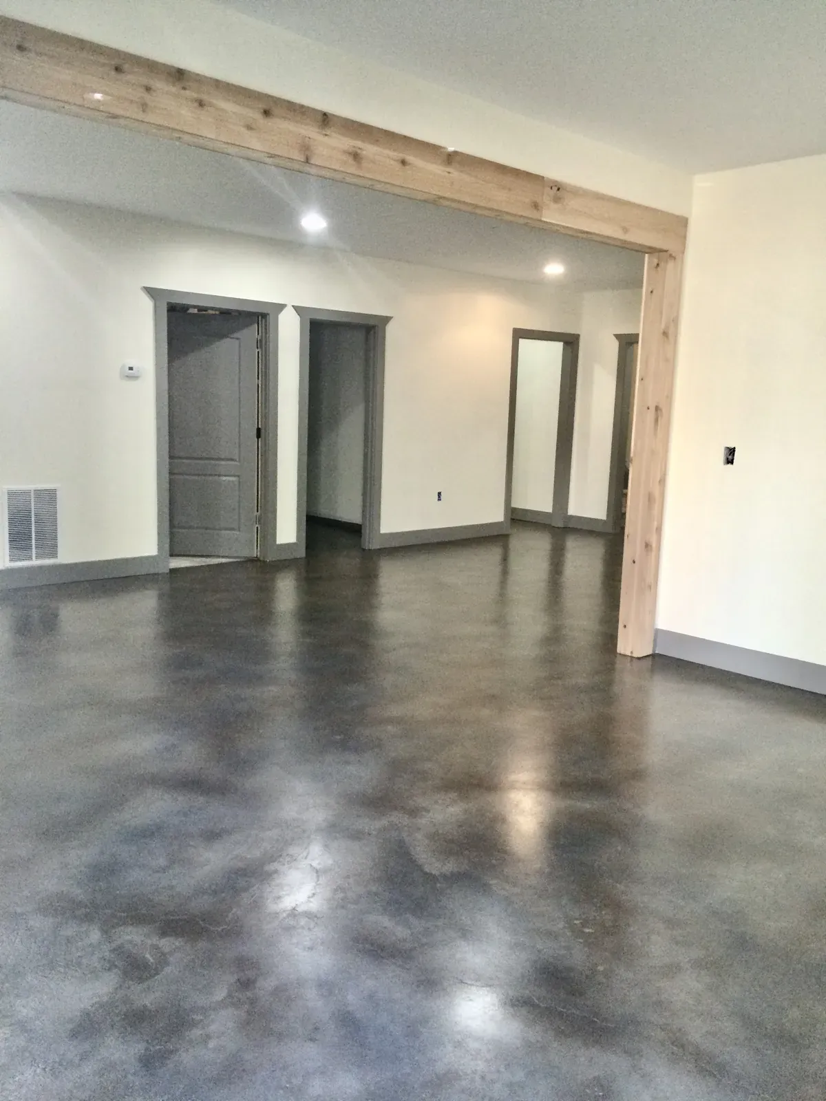 Deep charcoal stained concrete basement floor with a cedar beam in a Dallas GA home