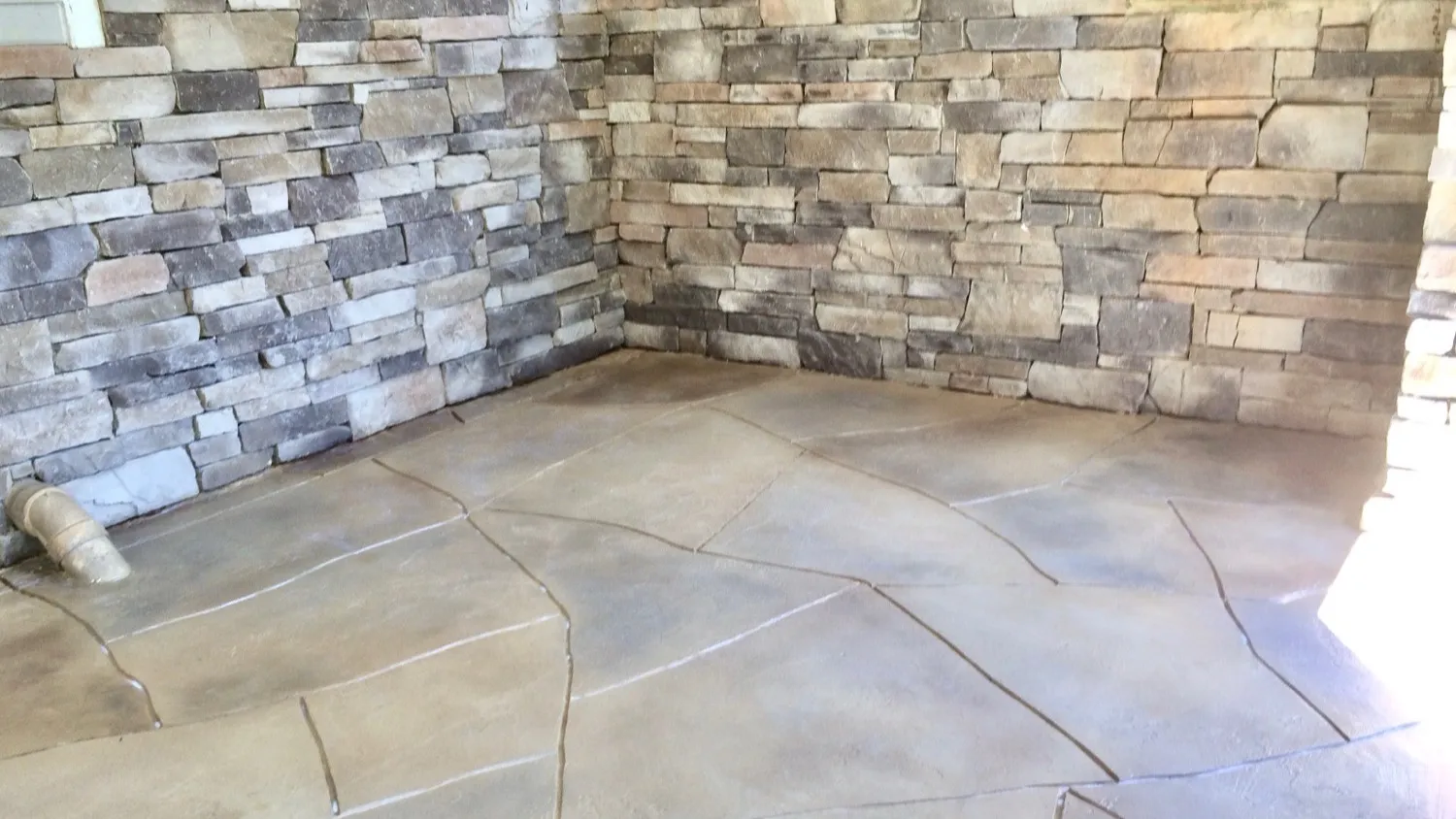 Faux-flagstone stained concrete patio with stacked-stone walls by JP Concrete Creations near Kennesaw, Georgia