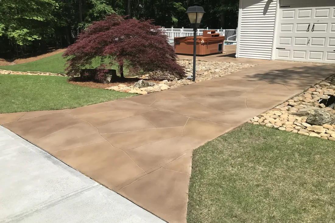 Stained concrete driveway with a rich earth-tone finish leading up to a suburban Georgia home